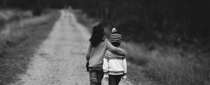 Two kids walking down a road in grey scale